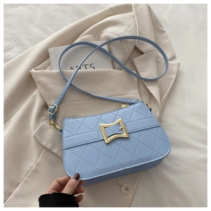Close-up of light blue quilted handbag with a large gold square buckle and chain strap