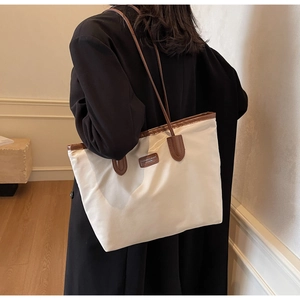 Rear view of a minimalist large tote bag with brown leather straps and fashion label