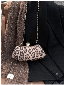 Dettaglio della borsa leopardata con chiusura a perla e catena d'oro su un blazer nero