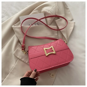 Detail of rose pink quilted crossbody bag with gold buckle on beige blazer background