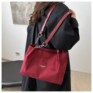 Close-up of deep red suede tote bag with leather chain strap and fashion label detail