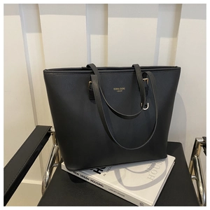 Détail du sac cabas noir montrant le cuir texturé croisé et le logo doré brillant