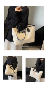 Close-up of a high-capacity cream tote bag with black leather straps and fashion label