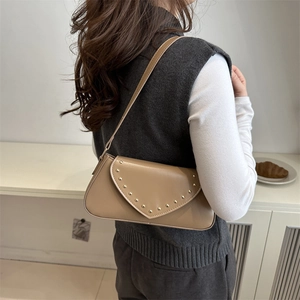 Vintage khaki underarm bag with gold rivets and flap closure shown on shoulder