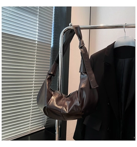 Close-up of a chocolate brown pleated hobo bag with knotted strap on a metal hanger