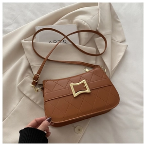 Detail of a brown quilted crossbody bag with golden metal buckle on a beige blazer