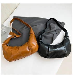 Close-up detail of pleated hobo bags in caramel and black glossy finish for women