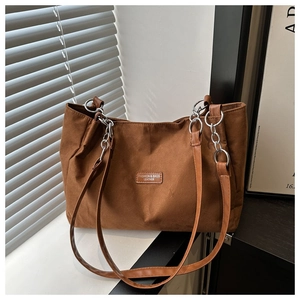 Detail of brown tote bag with silver chain strap and matte textured material finish