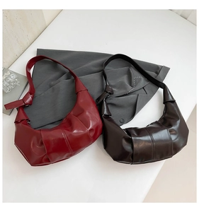 Close-up of pleated hobo bags in burgundy and dark brown with knotted strap details