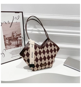 Detail of checkered tote bag with V-shaped opening, leather straps and decorative ribbon