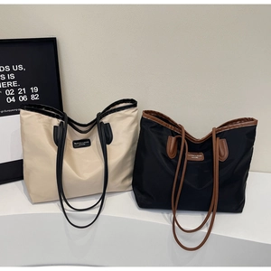 Detail of high-capacity waterproof tote bags featuring contrast leather trim and handles
