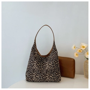 Detail view of large leopard print tote bag with brown leather straps and matching pouch