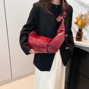 Chic burgundy crescent shoulder bag in glossy pleated leather with knot strap detail