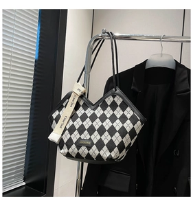 Detail of checkered tote bag featuring fashion ribbon and sleek black leather handles