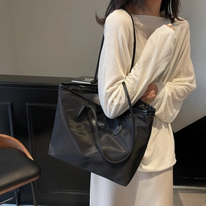 Minimalist black nylon tote bag with fashion tag and long shoulder straps for daily use