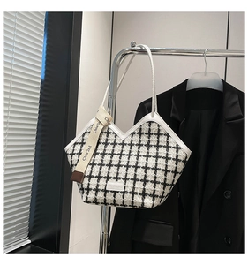 Close-up of black and white plaid tweed tote bag with decorative brand ribbon detail