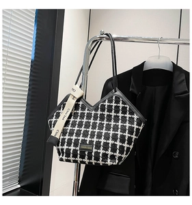 Detail of tweed checkered tote bag showing refined texture and stylish ribbon accent