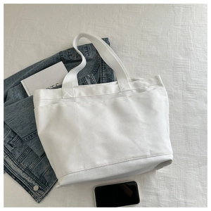 Top-down view of a large white canvas tote bag with triple external storage pockets