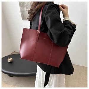 Detail shot of a burgundy matte tote bag with adjustable shoulder strap and gold buckle