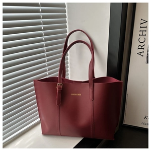 Close-up of burgundy tote bag with gold lettering and stitch details on PU leather