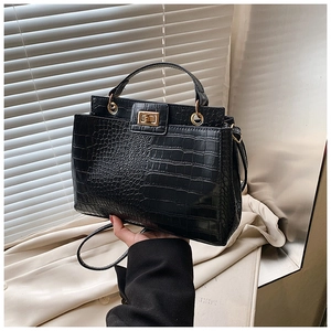 Detail of black crocodile texture handbag with golden swivel lock and top handle