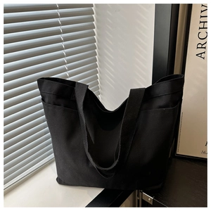Detail of black canvas tote bag showing side pockets and thick fabric texture