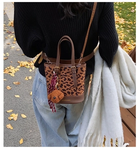 Detail of leopard print bucket bag with plush bear charm and faux leather accents
