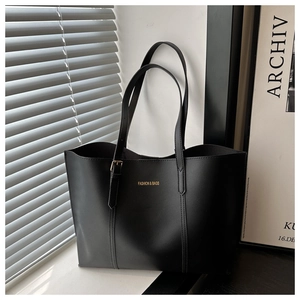 Detail of minimalist black leather tote bag featuring gold embossed text and slim straps