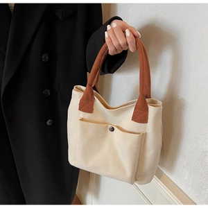 Gros plan du sac en toile beige avec sangle marron et bouton pression magnétique argenté