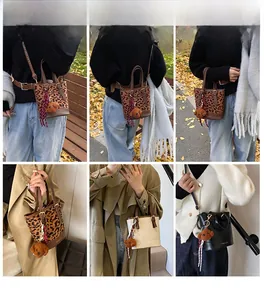 Close-up of three leopard print bucket bags with plush dog charms and leather straps
