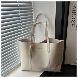 Detail of off-white leather tote bag featuring adjustable buckle and fashion logo text