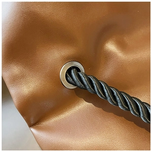 Detail view of brown leather tote with black twisted rope strap and silver metal grommet
