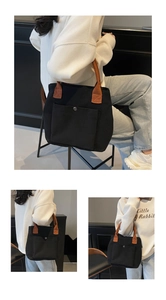 Détail du sac cabas en toile noire avec poche extérieure, bouton-pression et sangle brune
