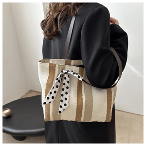 Striped canvas tote bag with polka dot ribbon detail and brown leather straps on model