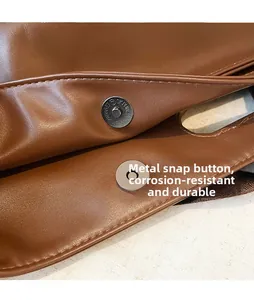 Detail shot of the magnetic metal buckle and fine stitching on the brown leather tote bag