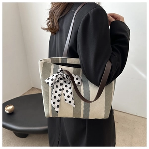Detail of striped canvas tote bag with leather strap and polka dot silk bow decoration