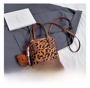 Detail of leopard print bucket bag with plush bear charm and checkered ribbon decor