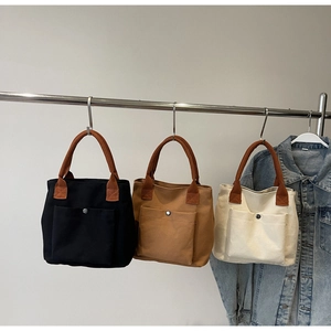 Trois sacs fourre-tout en toile noir, kaki et crème suspendus sur un support en métal