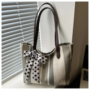Detail of striped canvas tote bag with brown leather handles and a polka dot silk scarf