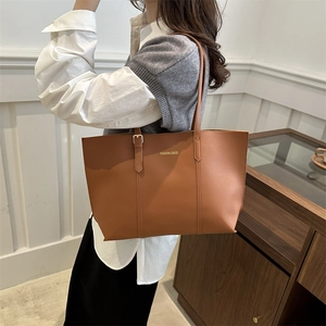Retro caramel brown leather tote bag with metal buckle detail shown on a model