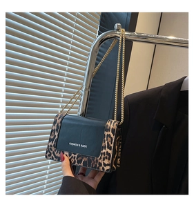 Detail of small leopard print bag with black leather stitching and gold chain strap