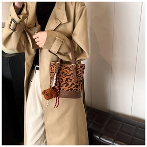 Detail of leopard print bucket bag with brown leather base and plush bear charm