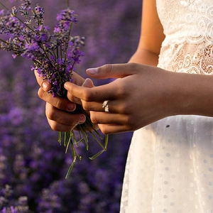 Close-up of golden leaf ring on hand against a dreamy lavender field background