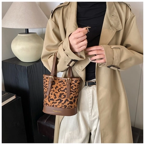 Detail of leopard print suede bucket bag with brown leather trim and metal buckles