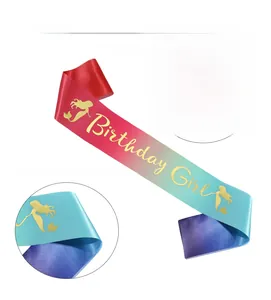 Close-up of golden Birthday Girl lettering and mermaid silhouettes on gradient satin sash