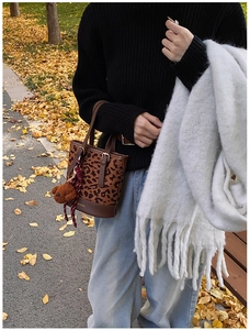 Close-up of leopard print bucket bag with leather handles and cute plush bear charm