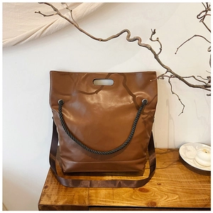 Detail of vintage brown tote bag with decorative thick rope and silver metal eyelets