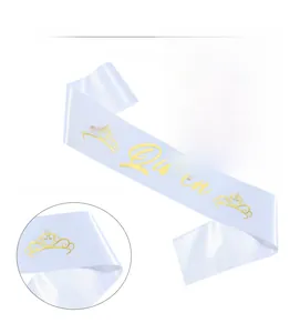Detailed view of white satin birthday sash with gold foil Queen text and crown graphic