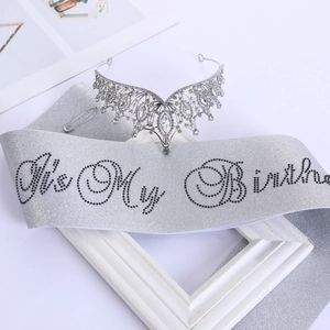 Dettaglio corona di compleanno argentata con strass e fascia con scritta glitter