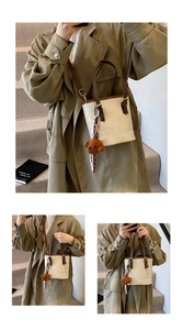 Detail of off-white bucket bag with brown leather handle and cute plush bear charm